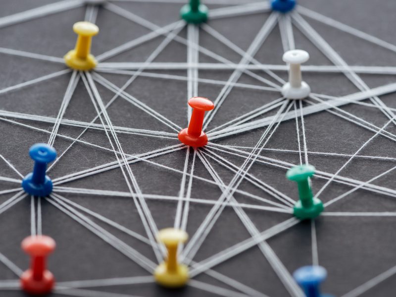colorful push pins connected with strings isolated on grey, network concept